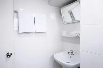 a white bathroom with a sink and a mirror at Annex Lumpini Bangkok in Bangkok
