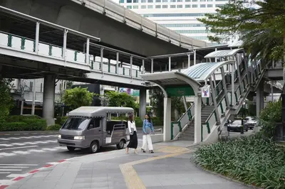 two people walking on a sidewalk next to a bus at Courtyard by Marriott Bangkok Sukhumvit 20 in Bangkok