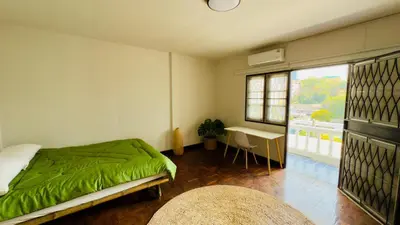 a bedroom with a bed and a table and a window at Creative Bangkok Balcony in Sathani Bang Khen