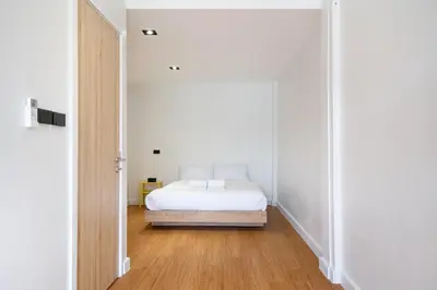 a bedroom with a white bed and a wooden floor at Townhouse in Khet Phayathai - Ari in Bangkok