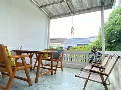 a patio with a wooden table and chairs on a balcony at Cheap house 7min next to BTS Kasetsart , 5 bedroom in Ban Yang