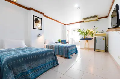 a bedroom with two beds and a television in it at Dancenter Howard Square Boutique Hotel in Bangkok
