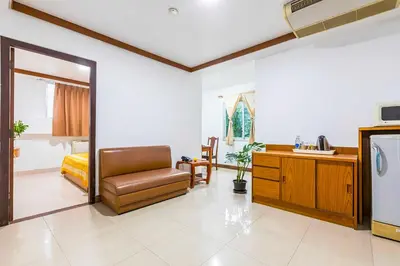 a living room with a tv and a chair and a desk at Dancenter Howard Square Boutique Hotel in Bangkok