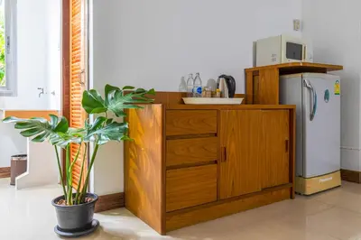 a kitchen with a wooden cabinet and a refrigerator at Dancenter Howard Square Boutique Hotel in Bangkok