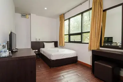 a bedroom with a bed and a desk and window at Dancenter Khaosan Park Hotel in Bangkok