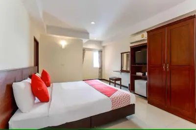 a bedroom with a bed with red pillows and a cabinet at Dancenter VResotel in Bangkok