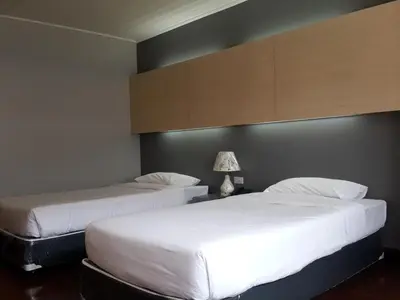 two beds in a hotel room with white sheets at Florida Hotel in Bangkok