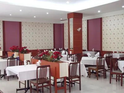 a restaurant with white tables and chairs and purple walls at Florida Hotel in Bangkok
