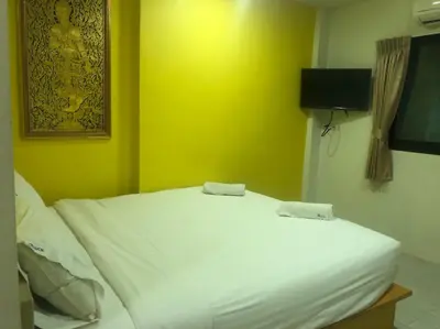 a white bed in a room with a yellow wall at The Seven Luck in Bangkok