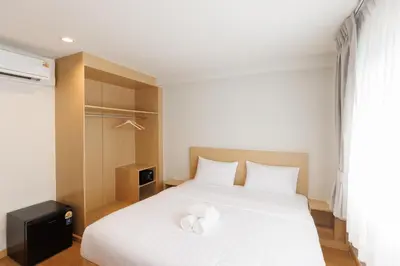 a bedroom with a white bed with two towels on it at Takka Hotel - Bearing in Bangna