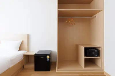 a bedroom with a bed and a small cabinet with a microwave at Takka Hotel - Bearing in Bangna
