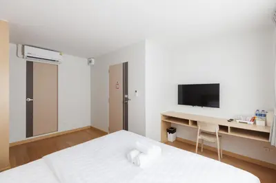 a white bedroom with a desk and a bed at Takka Hotel - Bearing in Bangna