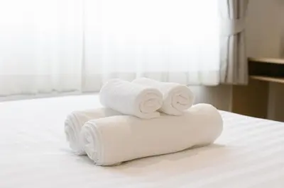 a pile of towels sitting on top of a bed at Takka Hotel - Bearing in Bangna