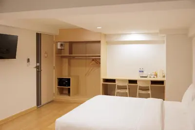 a bedroom with a white bed and a kitchen at Takka Hotel - Bearing in Bangna
