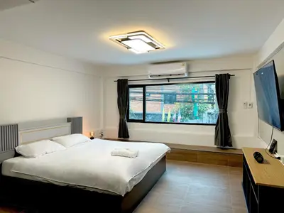 a bedroom with a large bed and a window at Berlin Haus in Nonthaburi