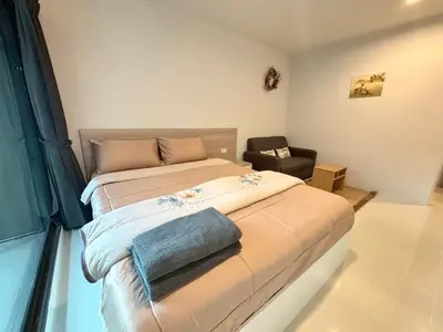 a bedroom with a large bed and a chair at 4 mins to MRT Sutthisan in Bangkok