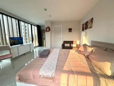 a bedroom with a large bed in a room with large windows at 4 mins to MRT Sutthisan in Bangkok