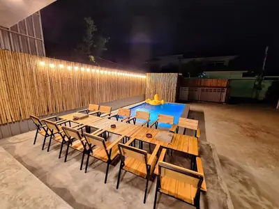 a long wooden table and chairs in a patio at Number 8 Poolvilla Bangkok in Sathani Ban Hua Mak