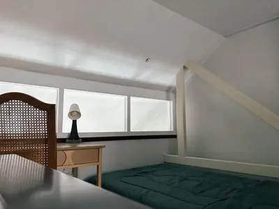 a bedroom with a bed and a desk and a window at SuXiang - Chinatown, Bangkok in Bangkok