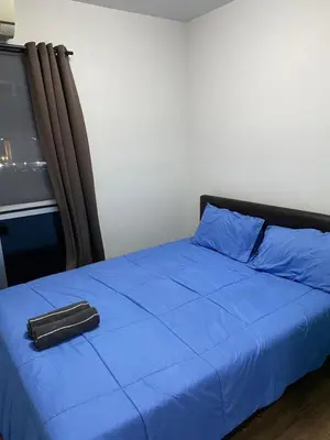 a bed with a blue comforter and a pillow on it at Mari's space city view in Nonthaburi