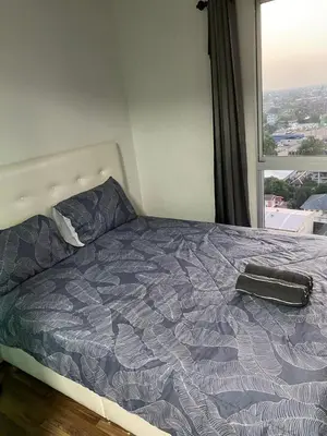 a bed in a bedroom with a large window at Mari's space city view in Nonthaburi