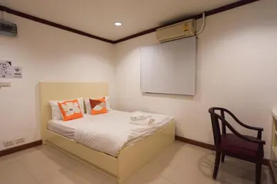 a small bedroom with a bed and a chair at Sampheng House in Bangkok