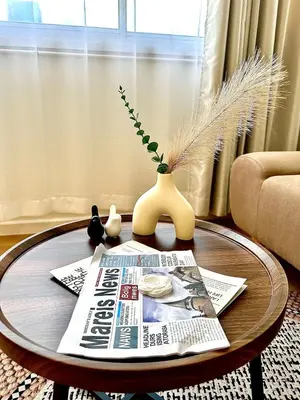 a coffee table with a news paper and a vase on it at CinCin Popular Condo in Thung Si Kan