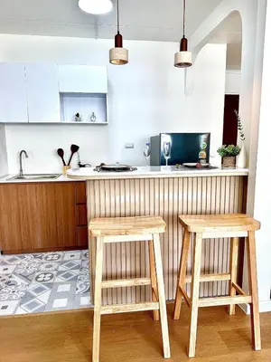 a kitchen with two wooden stools in front of a counter at CinCin Popular Condo in Thung Si Kan