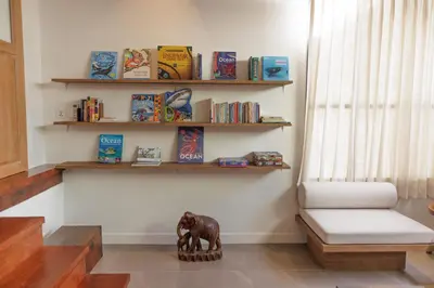 a room with a bench and shelves with books at Baan Manee BKK in Bangkok