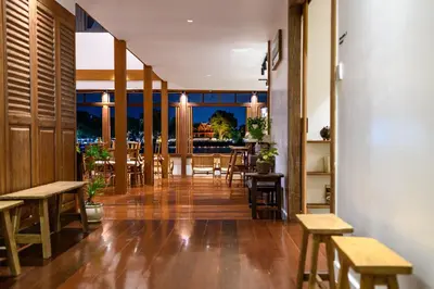 a restaurant with wooden tables and chairs and a balcony at Baan Manee BKK in Bangkok