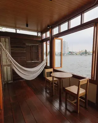 a hammock on a boat with a table and chairs at Baan Manee BKK in Bangkok