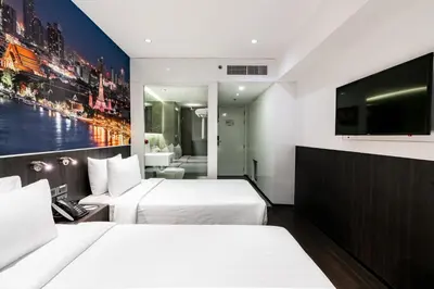 a hotel room with two beds and a flat screen tv at Galleria 12 Sukhumvit Bangkok by Compass Hospitality in Bangkok