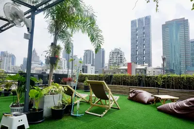 a patio with chairs and plants and a city skyline at Hash Capsule Hostel Silom Soi 3 in Bangkok