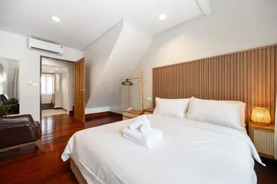 a bedroom with a large white bed with a wooden headboard at Moondance House Chinatown in Bangkok
