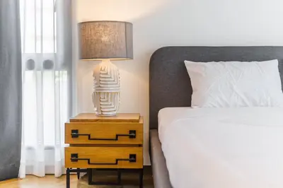 a lamp on a night stand next to a bed at Designer 49 Pool Villa in Bangkok