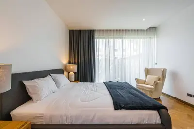 a bedroom with a bed and a chair and a window at Designer 49 Pool Villa in Bangkok