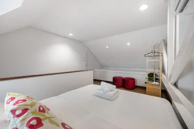 a small white room with a bed and a window at Sunfire House Chinatown in Bangkok