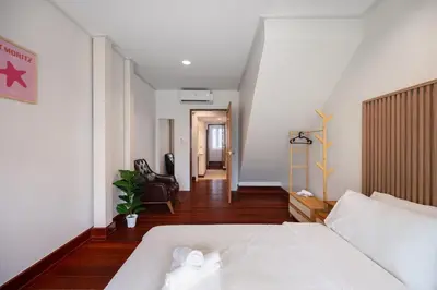 a bedroom with a white bed and a hallway at Sunfire House Chinatown in Bangkok