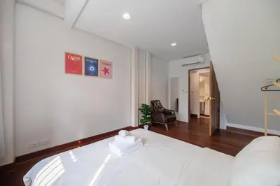 a bedroom with a white bed and a chair at Sunfire House Chinatown in Bangkok