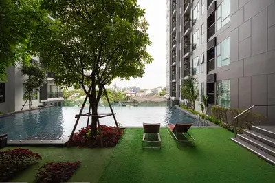 a swimming pool with chairs and a tree in a building at City Oasis: 5 Min to Metro, Pool & Gym, Essentials in Khlong Toei