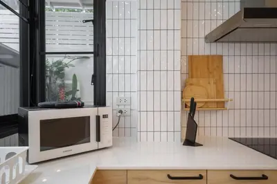 a microwave sitting on top of a kitchen counter at Ayas Retreat - Muji Ekkamai Pool Villa with 4 bedrooms in Khlong Toei