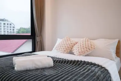 a bedroom with a bed with pillows and a window at Ayas Retreat - Muji Ekkamai Pool Villa with 4 bedrooms in Khlong Toei