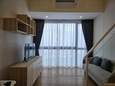 a living room with a couch and a large window at Rama9 Loft Life in Bangkok