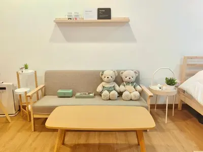 two teddy bears sitting on a couch in a bedroom at Secret Muji Vintage Building ห้องลับมูจิในตึกวินเทจ in Ban Song Hong