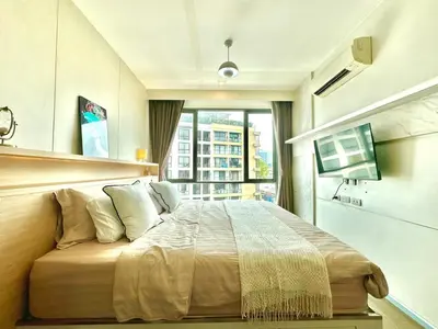 a bedroom with a large bed with a window at Bright & Spacious Apartment in Bangkok