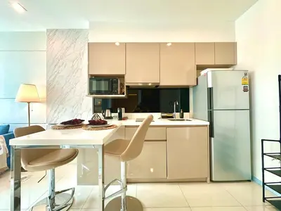 a kitchen with a table and chairs and a refrigerator at Bright & Spacious Apartment in Bangkok