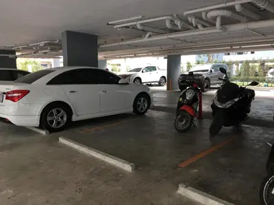 a white car parked in a parking lot next to a scooter at White Turquoise -1 Bedroom Apartment- in Bangkok