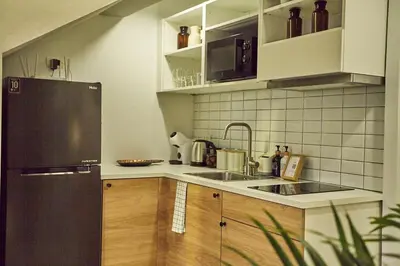 a kitchen with a black refrigerator and wooden cabinets at Stylish duplex 2 BR apartment - 3 mins walk to BTS Nana in Bangkok