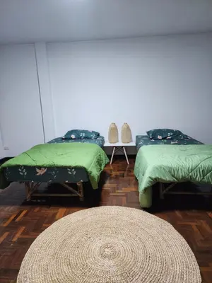 two beds with green covers in a room with a rug at Creative Bangkok twin bed in Sathani Bang Khen