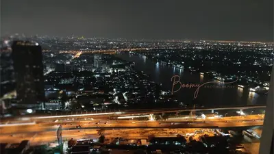 a view of a city at night with a river at Luxury Riverside Condo, 3 SKY Pools , Close to MRT Train Station in Ban Sai Ma